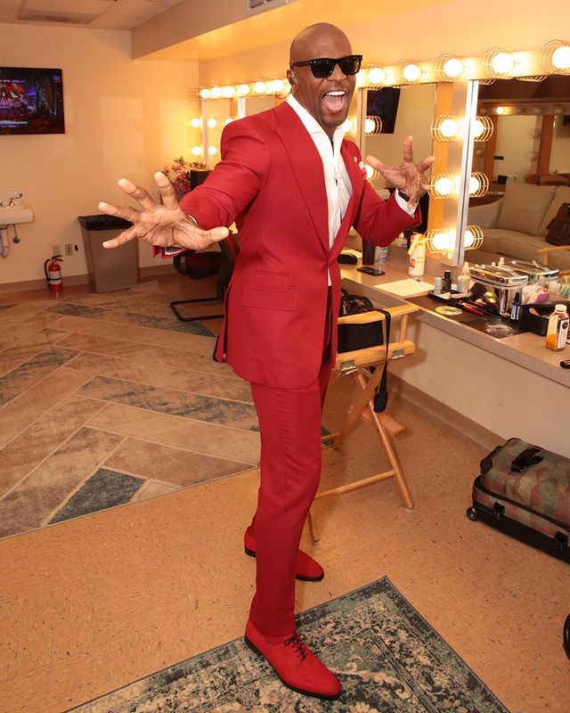 terry crews is wearing red suit and white tee.